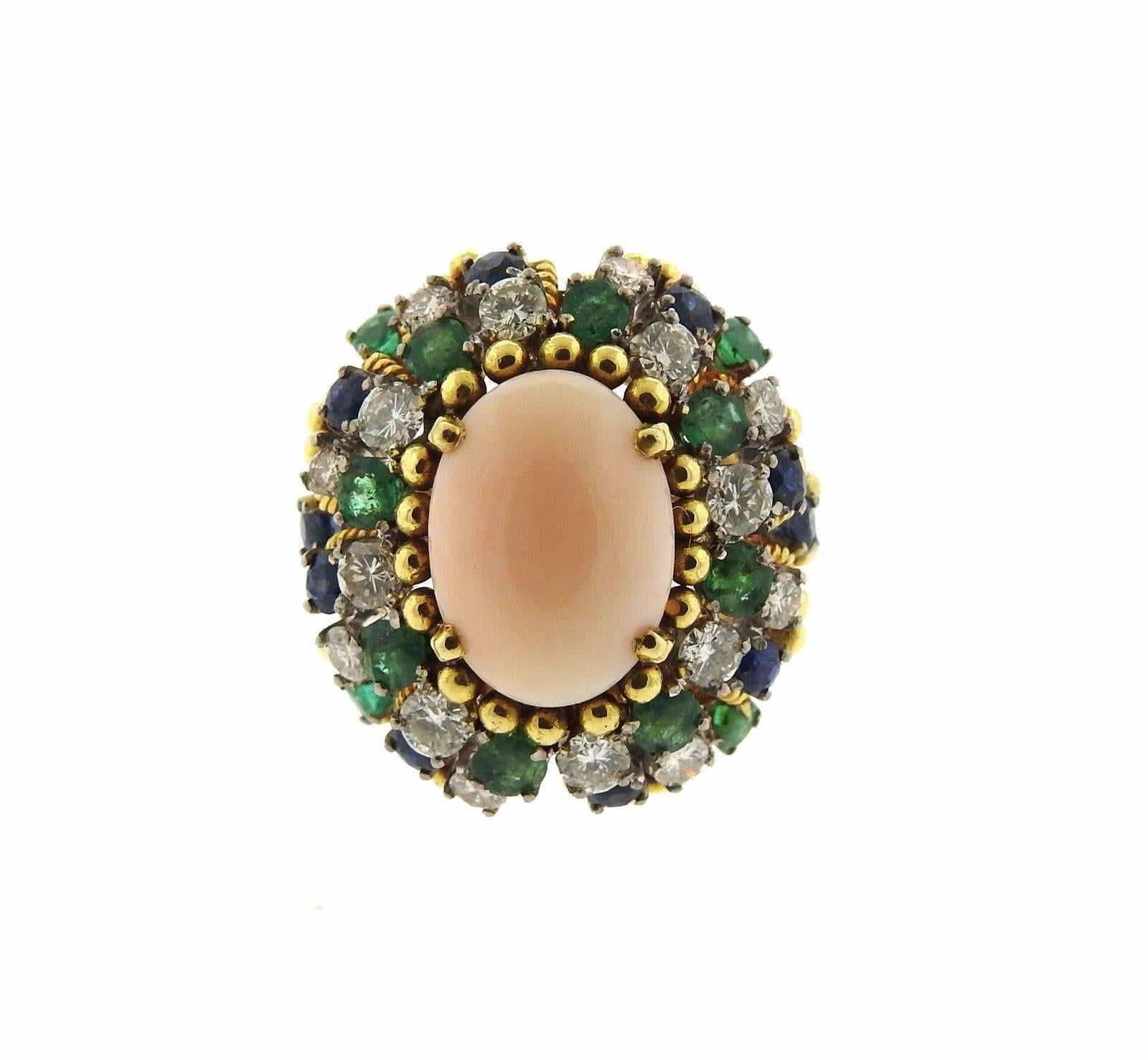 Lovely 18k Gold angel skin coral ring from the 1960's featuring 1.20ctw in diamonds, emeralds, and sapphires. Ring is a size - 6, measures 24mm at widest point. Marked 18k and weighs 21.1 grams. 