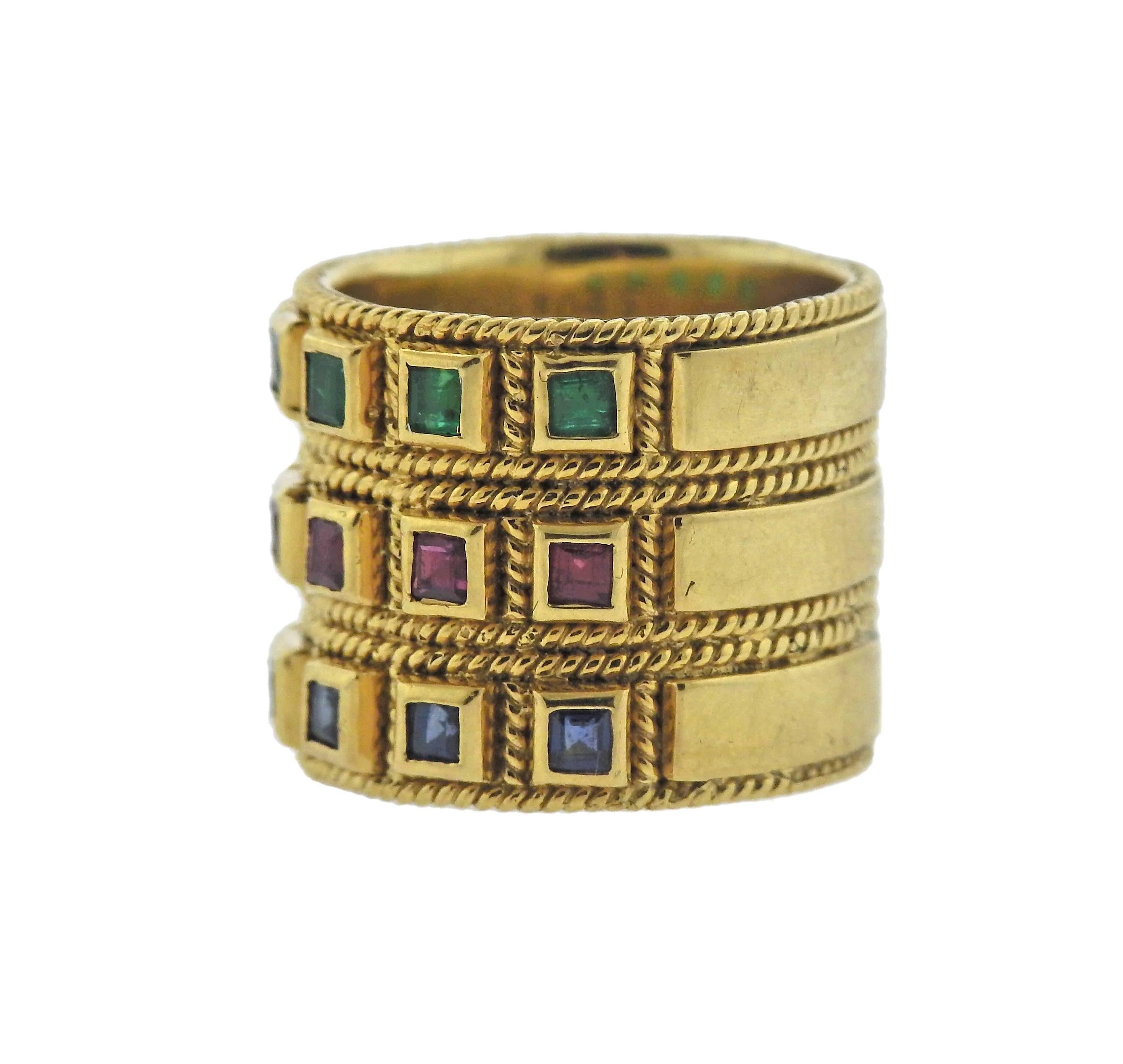 Wide 18k yellow gold band ring, set with 0.38ctw in emeralds, 0.45ctw in rubies and 0.51ctw in sapphires. Ring is a size 6 and 16.7mm wide. Marked: E0.38, R0.45, S0.51, 750 k18. Weight of the piece - 19.6 grams. 