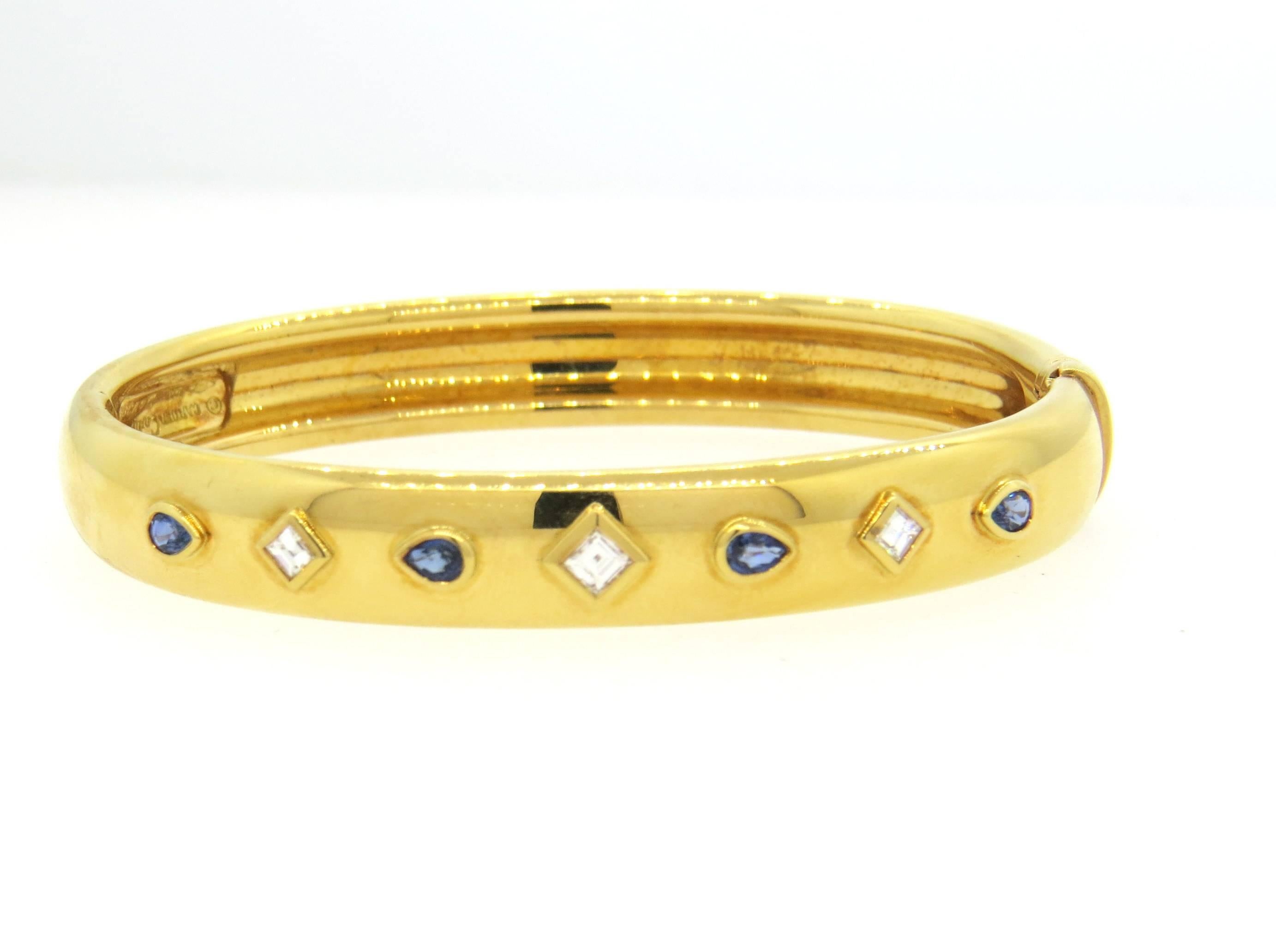 18k yellow gold bangle, crafted by Cartier, set with blue sapphires and  diamonds. Bracelet will comfortably fit up to 6 1/2