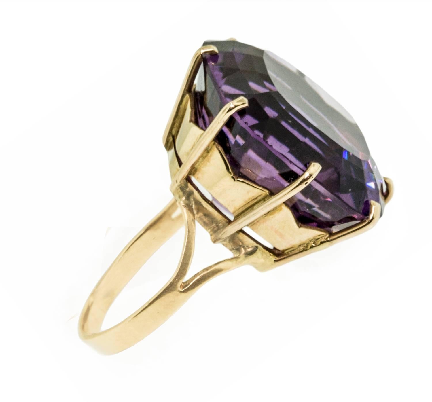 This striking ring is set in 14k yellow gold. The beautifully designed hand made mount holds a intense purple cushion cut amethyst weighing just over 32 cts. This ring measures size 5 and is in excellent condition.