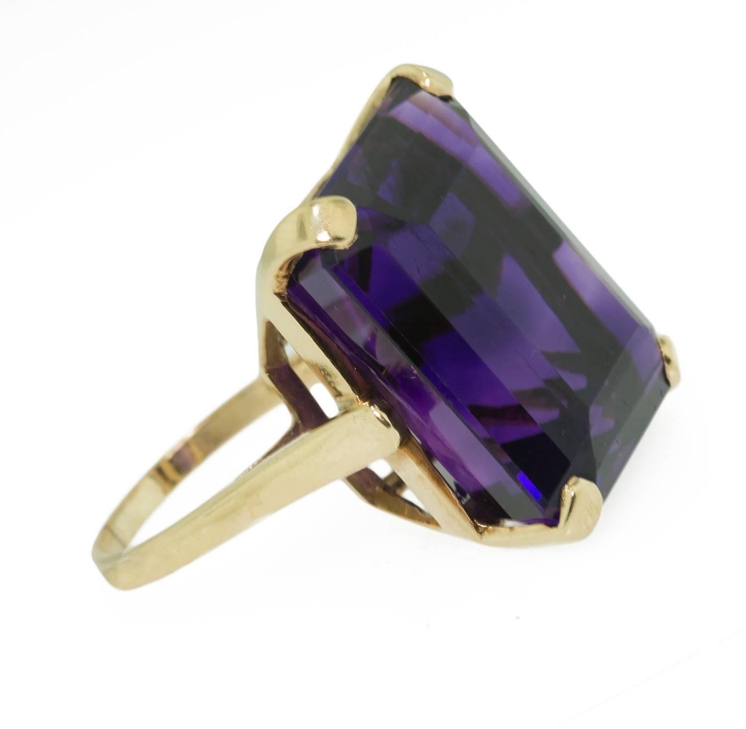 This large, dramatic amethyst ring is an intense deep purple. It is set in a custom made high basket 14k yellow gold mount. This ring is large and striking on the finger. It measures size 6 and in excellent condition.