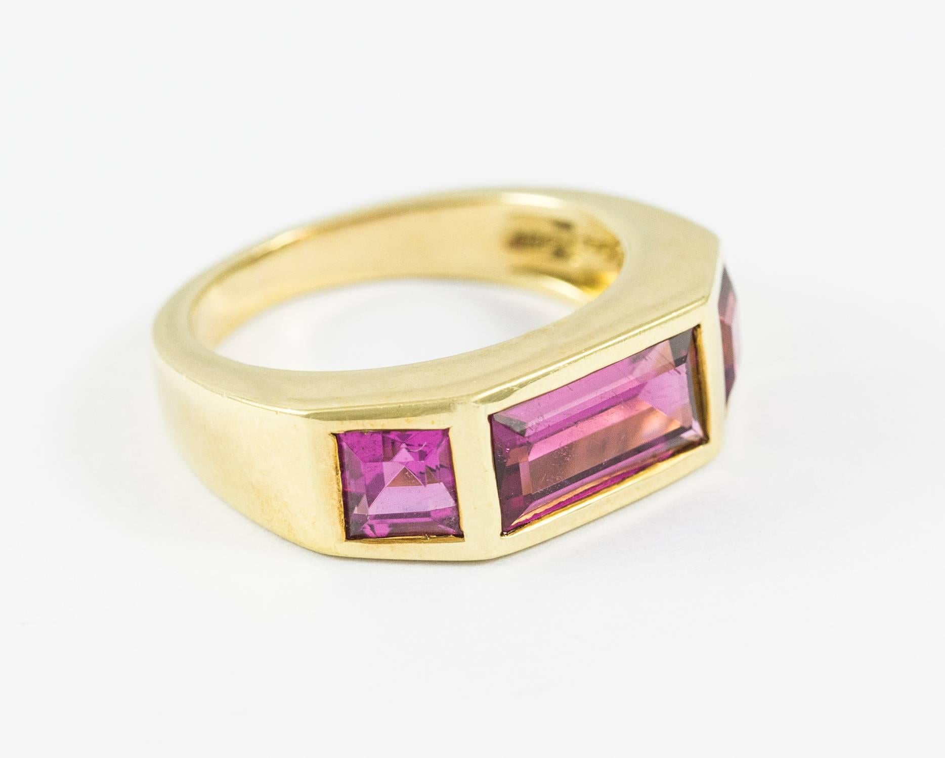 A stylized pink tourmaline ring by Paloma Picasso in 18k yellow gold. The total weight of the three square cut tourmaline's is 2.90 ct. The Tourmalines are intensely pink with vivid and strong saturation.Tailored and elegant this ring measures size