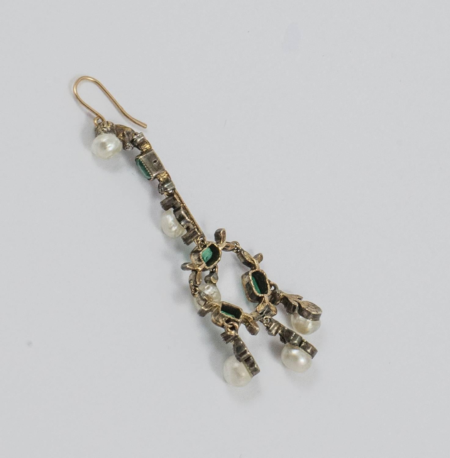 A pair of antique earrings set in 14k yellow gold with detailed design comprised of Emeralds, Pearls and Diamond chips. They are hand made with fine, delicate workmanship. The emeralds are bezel set in mill grain mounts and the tiny diamond chips
