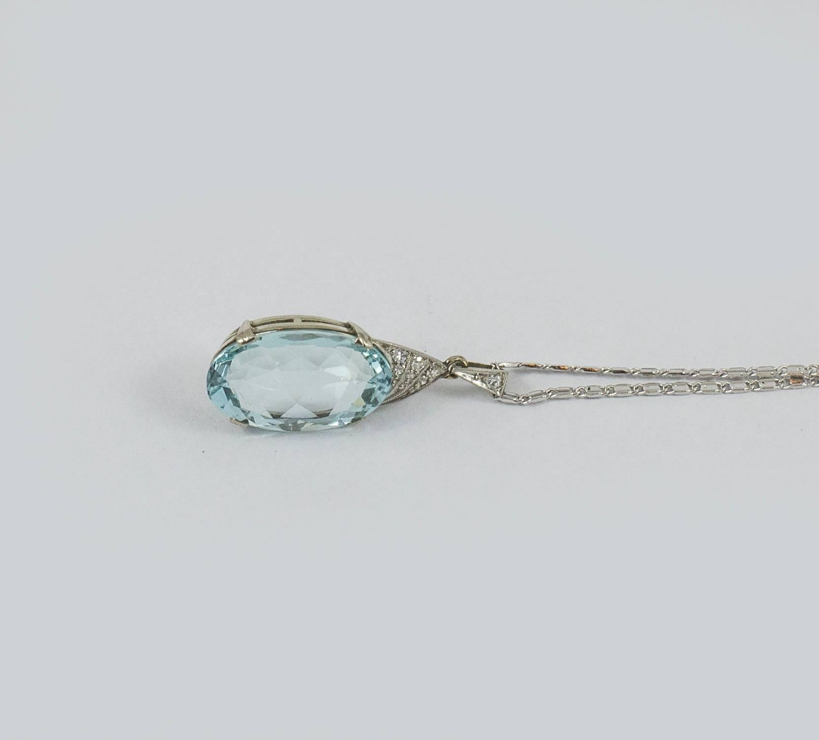 A delicate Art Nuveau aquamarine necklace. The faceted oval aquamarine weighs 10.80 ct and is set in 14kt white gold with fine diamond detail. This refined pendant is accompanied by a white gold chain measuring 18 inches. It is in excellent