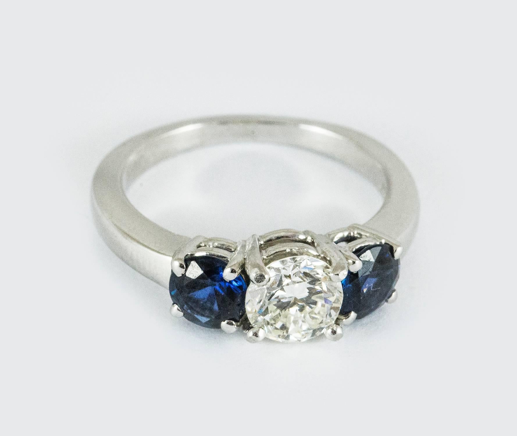 A classic three stone diamond and sapphire ring set in platinum. The central diamond weighs .83 (I colour, VS2 clarity). It is flanked on either side by two blue medium-dark toned sapphires. This ring is tailored and a classic. It measures size 5.5