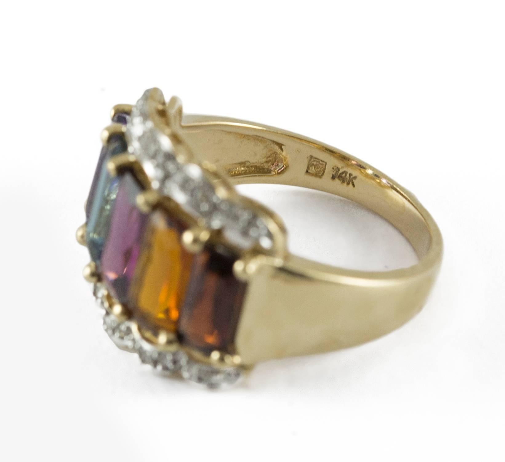 A bright gemstone ring set in 14k white and yellow gold. It holds 5 rectangular mixed cut semi precious stones. (garnet, citrine, tourmaline, topaz and amethyst). The border of the ring is enhanced by 26 round single cut diamonds. This ring is