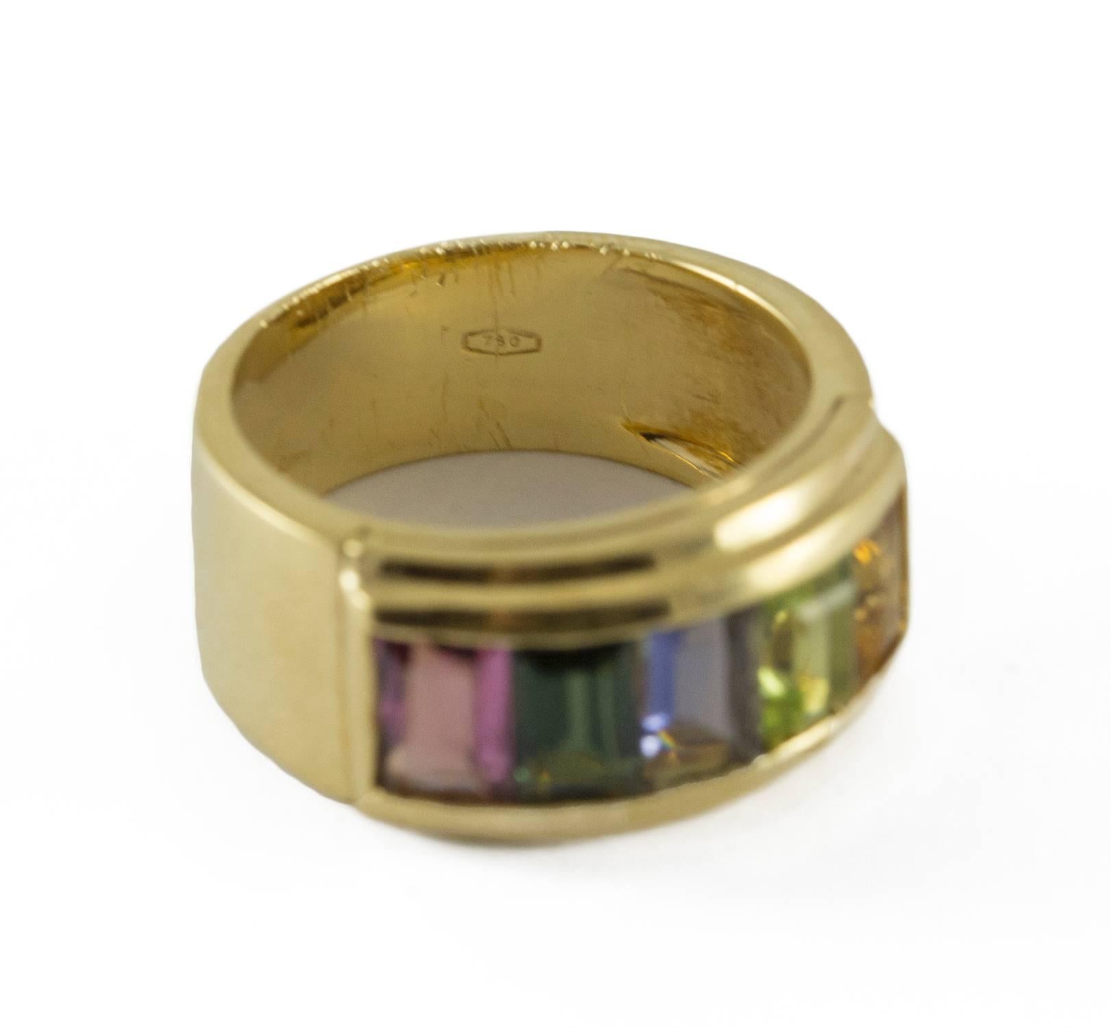 A delightful gemstone band ring set in 18k yellow gold. This ring holds bright luminous semi precious stones -  Pink Tourmaline, Green Tourmaline, Iolite, Peridot and Citrine. They are channel set and framed by yellow gold. The ring measures size