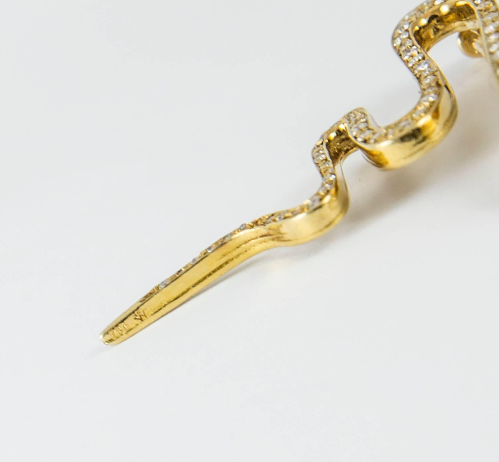 A handsome snake brooch set in 18k yellow gold. It holds 95 round brilliant cut diamonds (.85, G-H-I, VS-SI). A bright red ruby is set on the top of his head forming a striking medallion. The brooch measures 2.5 inches in length and 1.5 inches