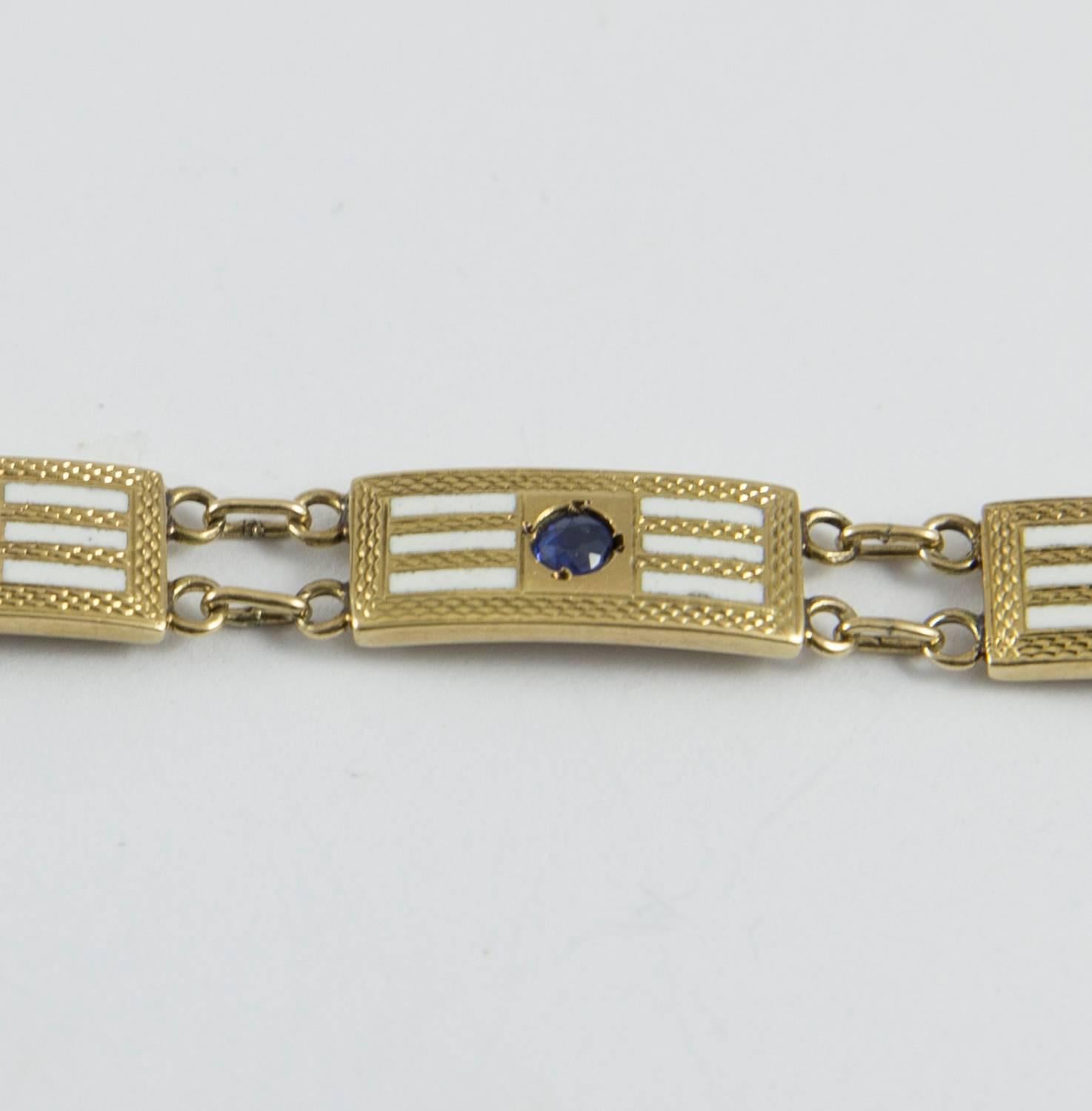 A charming Art Deco bracelet consisting of 9 links. Each link is designed with a round cut sapphire centered in a gold plaque with fine enamel lines and hand decorated gold detail. The sapphire range in tone from mid blue to deep intense indigo. The