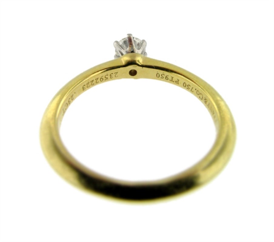 This charming Tiffany&Co. ring is set in yellow gold. It contains a beautiful little near perfect diamond. .23 E-F VS1. The mount is a classic knife edge design. This ring was made circa 1975. It is size 4.5 and is in excellent condition.