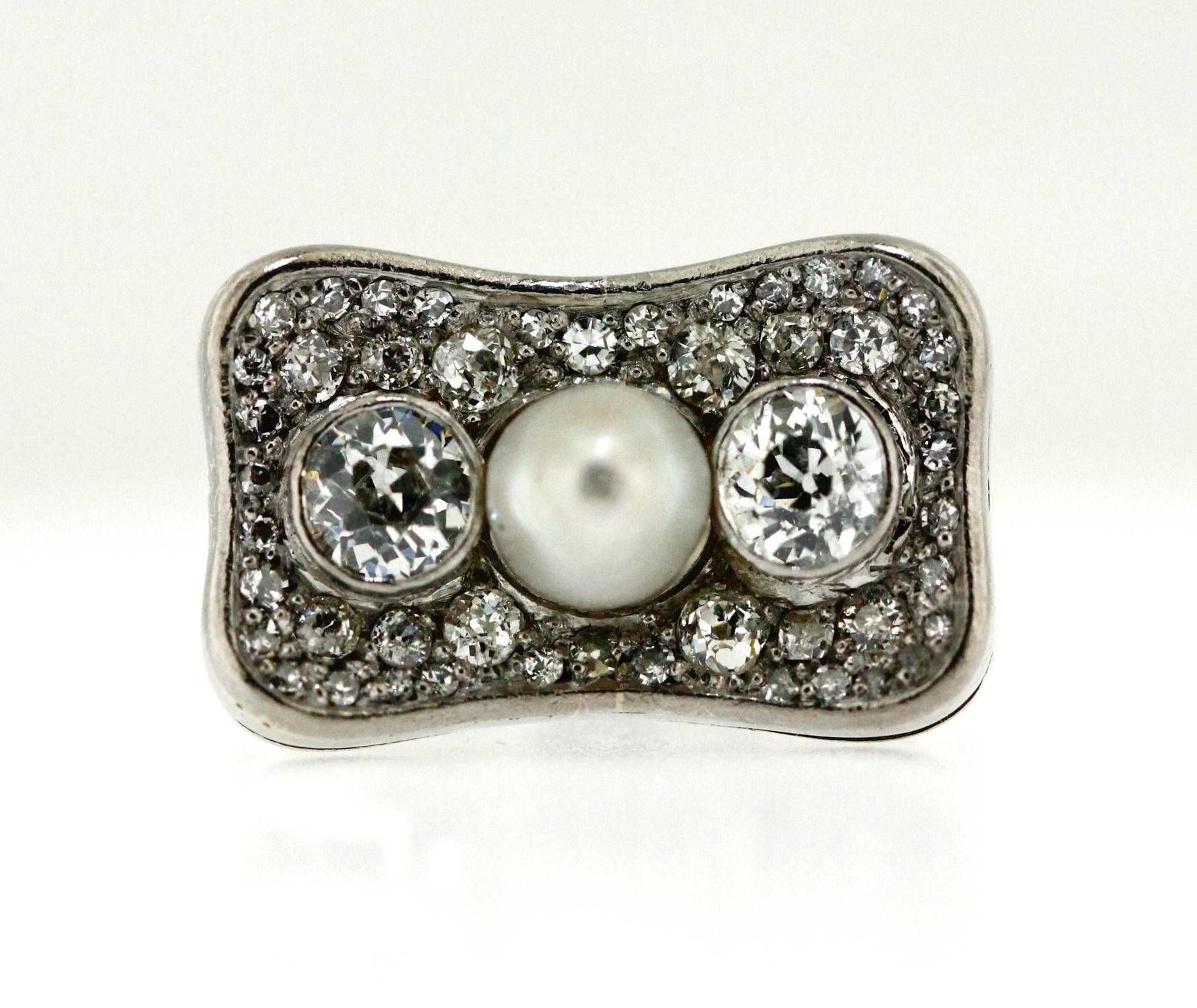 Set in 18KT white gold, this hand made ring holds a natural pearl, 6-6.5mm. It is clearly stamped SCHILLING. Either side of this silvery white natural pearl are 2 old European cut diamonds bezel set and weighing just under 1ct. They are a high F-G