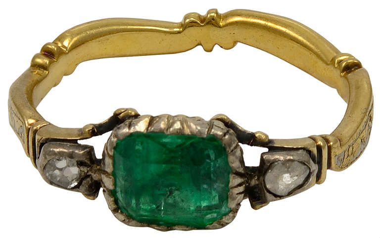 A  elegant  Georgian Emerald and Diamond ring in 20kt gold and silver, set with a emerald flanked by two rose cut diamonds, set in silver.The emerald is closed-set with a basket style setting, typical of the mid 18th century and is a magnificent