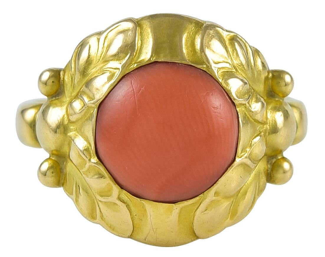 Georg Jensen Ring No. 111B with Coral.  This ring originally was designed by Georg Jensen in 1906.  This ring is in 18 karat yellow gold and coral.  This ring is size 7.5.  The ring bears impressed company marks for Georg Jensen circa 1933-1944,