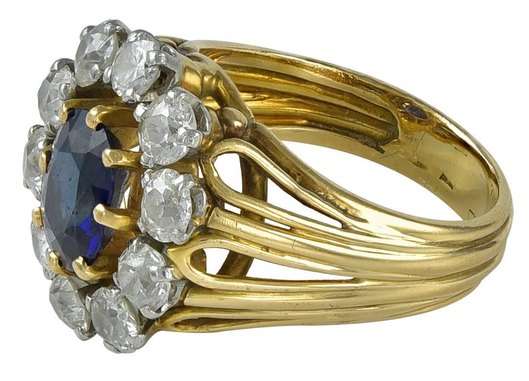Gold Cocktail Ring with Diamonds and Sapphire. This lovely ring is in 18 karat yellow gold set with ten round brilliant diamond surrounding an facetted sapphire.  The total diamond weight is 2 carats.  The ring is size 6.  The ring is in excellent