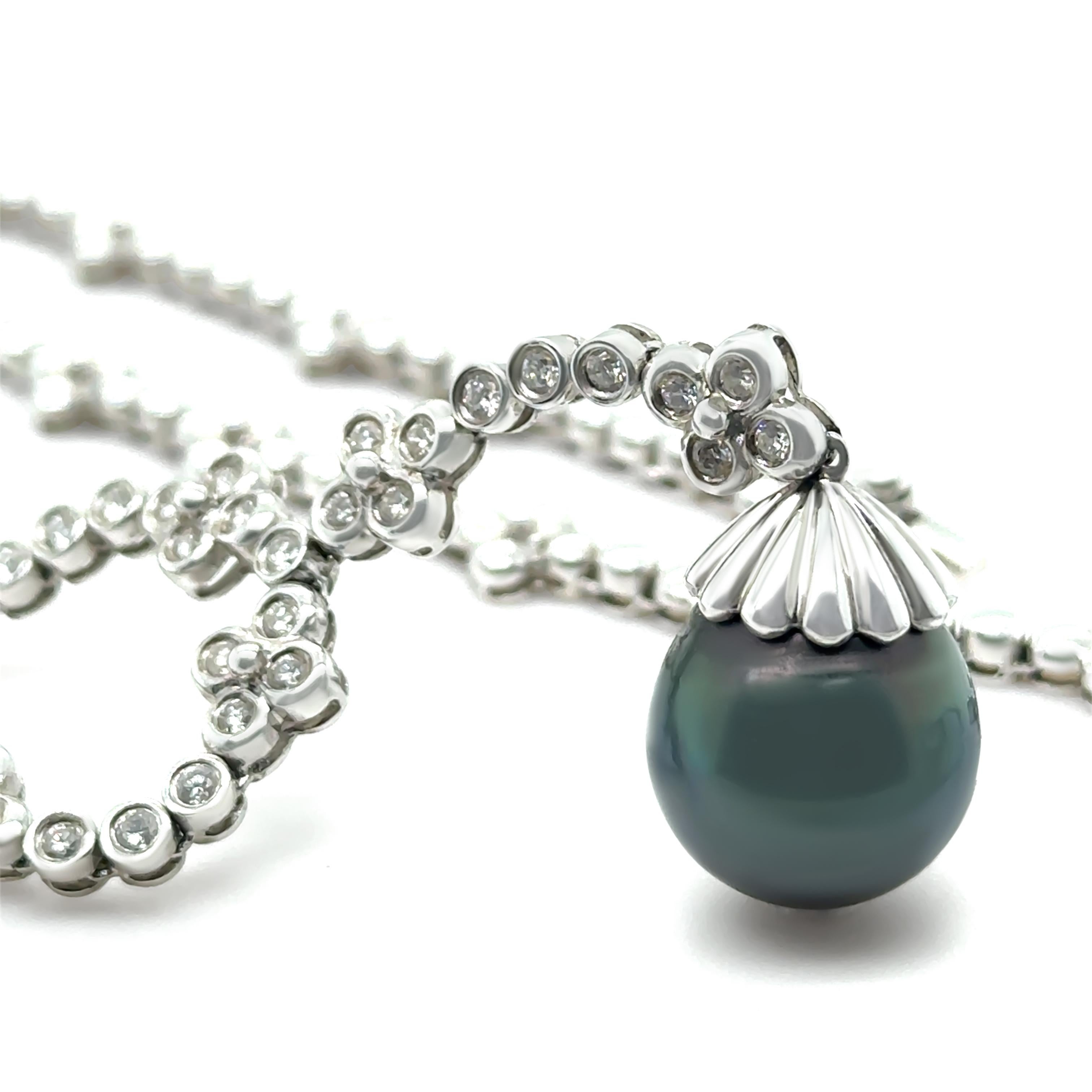 Questa elegante collana in stile lariat è realizzata in oro bianco 18 ct e mette in mostra un'affascinante perla di Tahiti a forma di goccia di 13,5 mm con segni naturali, colore nero del corpo e una splendida lucentezza. Sospesa da una goccia di
