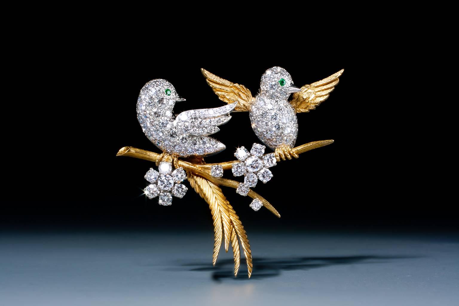 A very cute emerald and diamond bird brooch by McTeigue, depicting two birds perched on a branch, their platinum bodies pave set with brilliant cut diamonds and two circular cut emerald eyes and tail feathers of textured gold. Circa 1960.				
Total