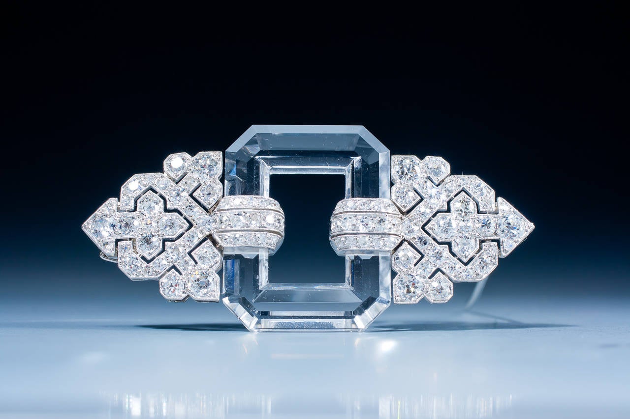 A very fine Art Deco rock crystal and diamond brooch by Linzeler & Marchak, centered by a faceted rock crystal open plaque, decorated on each side with diamond-set palmette motifs, mounted in platinum and gold. The mount shows the typical 'mille