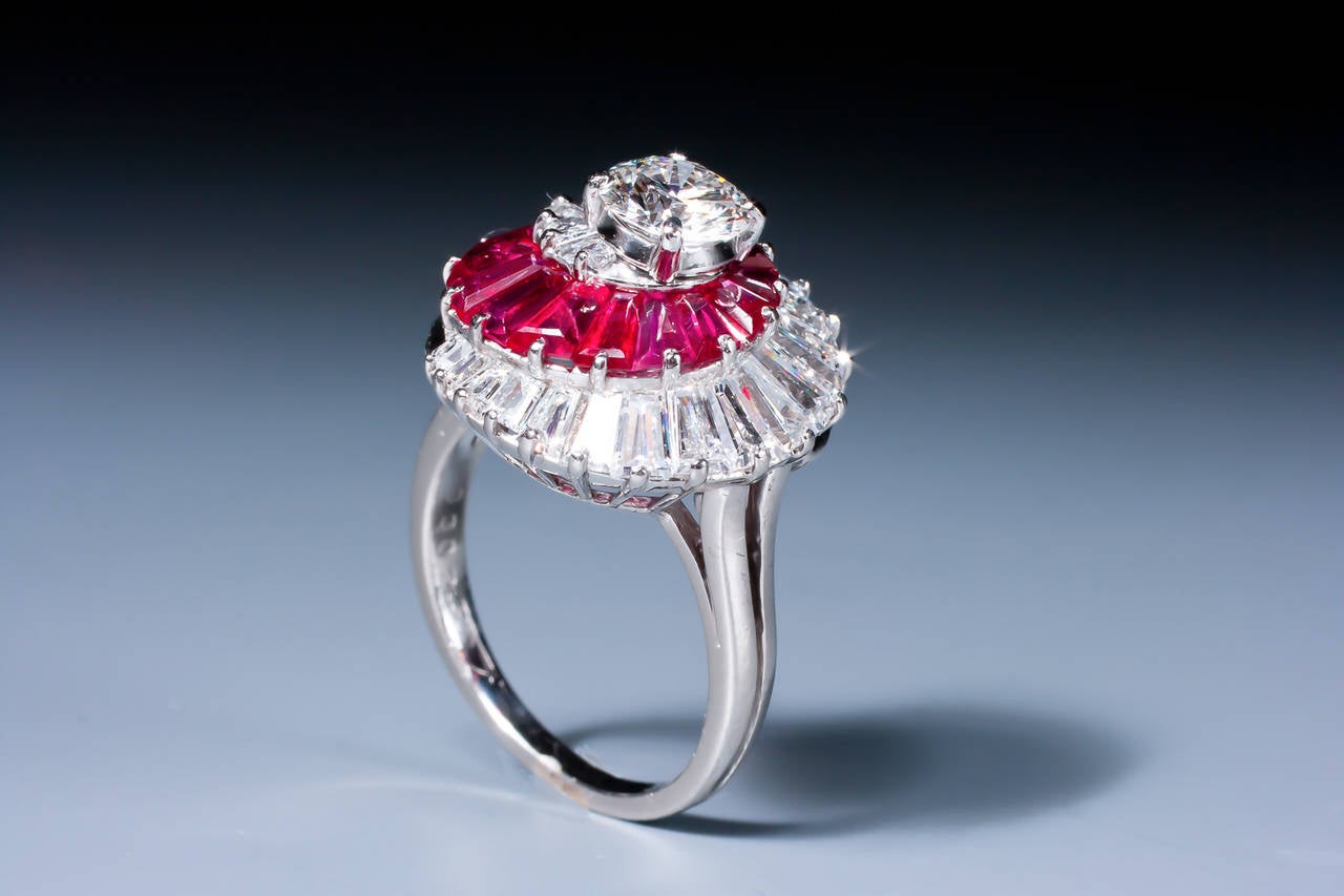 An unusual Op Art ruby and diamond whirl ring by Oscar Heyman & Brothers, centered by a brilliant cut diamond weighing 0.84 ct., enhanced by tapered baguette-cut diamonds, accented by tapered baguette-cut rubies, mounted in platinum. 

Although