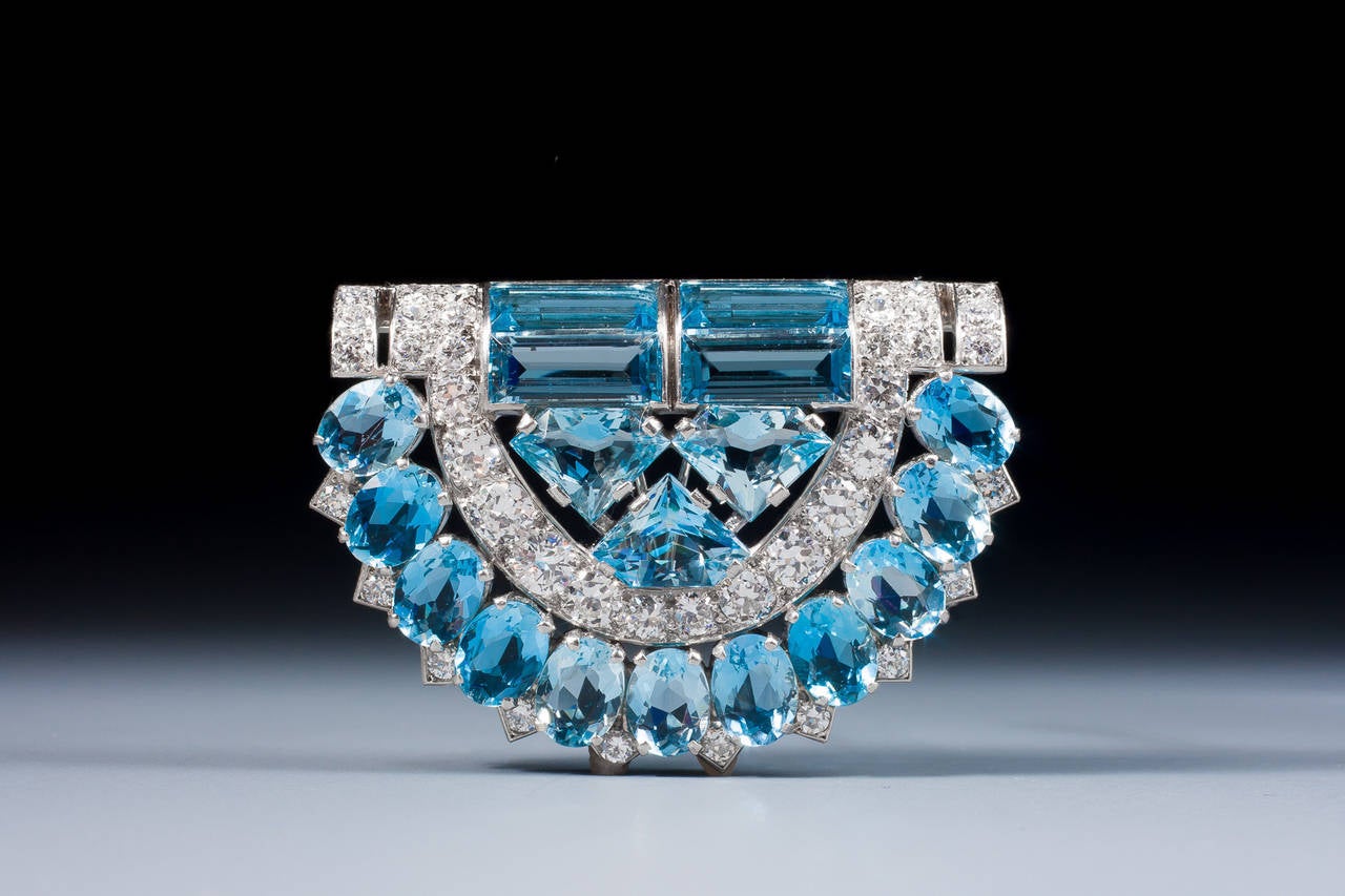 A very fine Art Deco aquamarine and diamond clip brooch by Cartier London of geometric design, set with oval, baguette and kite-shaped aquamarines and circular cut diamonds, mounted in platinum.
Signed Cartier London. In original Cartier fitted