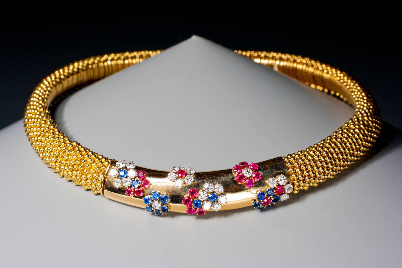A beautiful ruby, sapphire and diamond 'couscous' necklace by Van Cleef & Arpels, the flexible collar of gold beadwork linking decorated centrally with a polished gold segment of curved form studded with 'Hawaii' florets of round rubies, sapphires