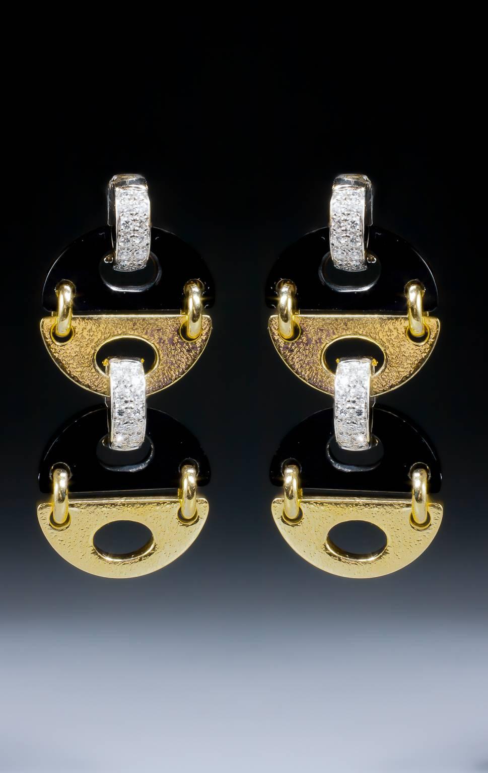 A funky pair of gold, onyx and diamond earrings,composed of pierced onyx and hammered gold half circles with pavé-set brilliant cut diamond connectors, mounted in 18 karat gold. 
Marked 'ITALY' , 18K stands for 18 karat gold.
Total diamond