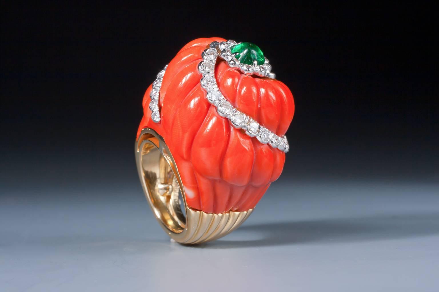 An impressive coral, emerald and diamond dome ring, the fluted coral highlighted by a diamond swirl, topped by a cabochon emerald in a diamond surround, mounted in platinum and 18 karat yellow gold.
 Total diamond weight: approx 1,25 ct.

New