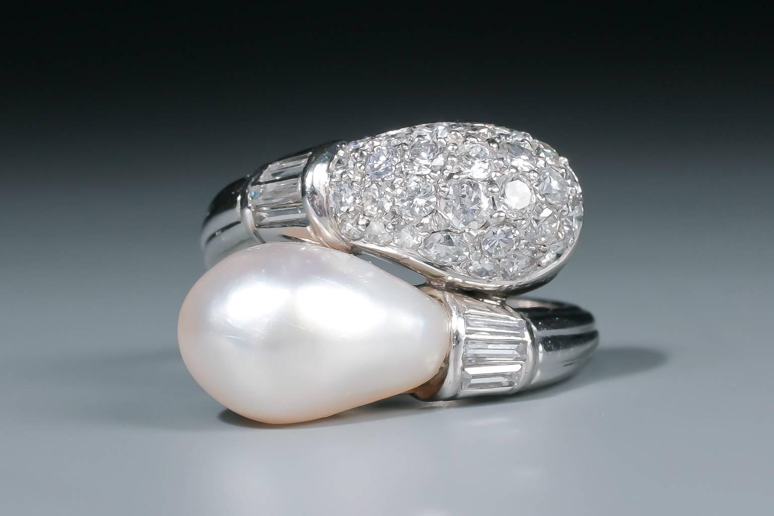 An unusual and elegant Art Deco natural pearl and diamond ring of crossover design, composed of a large drop shaped natural pearl and a diamond pavé-set drop shaped dome, flanked by baguette cut diamonds, mounted in platinum.
The pearl is