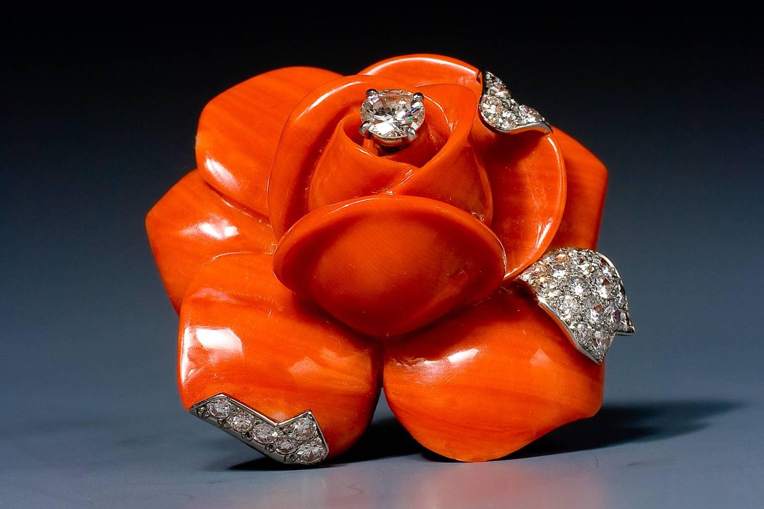 A striking coral and diamond flower brooch by Cartier, depicting a carved coral rose, the petals with brilliant cut diamond details and brilliant cut diamond dew drop, mounted in platinum and 18 karat gold.
In original fitted Cartier