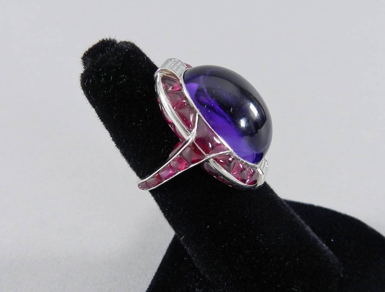 Verdura 1930’s vintage Art Deco platinum cocktail ring with ruby, diamond, and amethyst cabochon. Ring size 6 ¼. Decorated with rubies on reverse of ring and on exterior band. Approximately 8-10 carats of ruby, 23.31 carats amethyst cabochon, 1