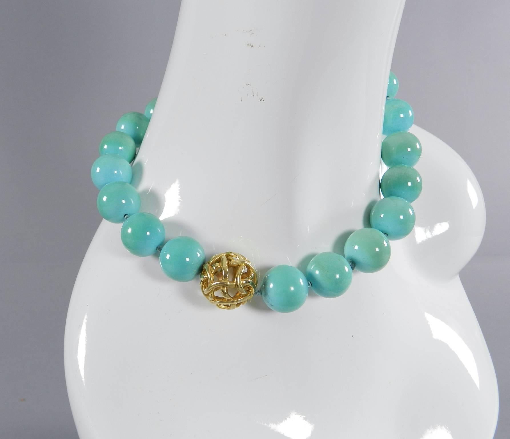Angela Cummings turquoise bead necklace with 18k yellow gold clasp.  21greenish blue turquoise beads that measures 17mm. Caged ball clasp measures 22mm. Measures 17.25