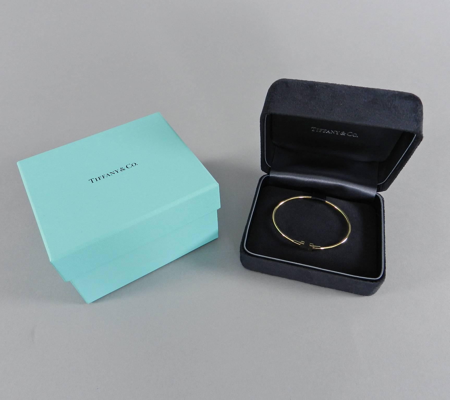 Tiffany and Co 18k yellow gold Narrow T wire bracelet. Brand new - received as a gift and never worn. Includes original black velvet box and blue Tiffany box. Size small. Measures 6-1/8" interior circumference (155 mm) and Tiffany website says