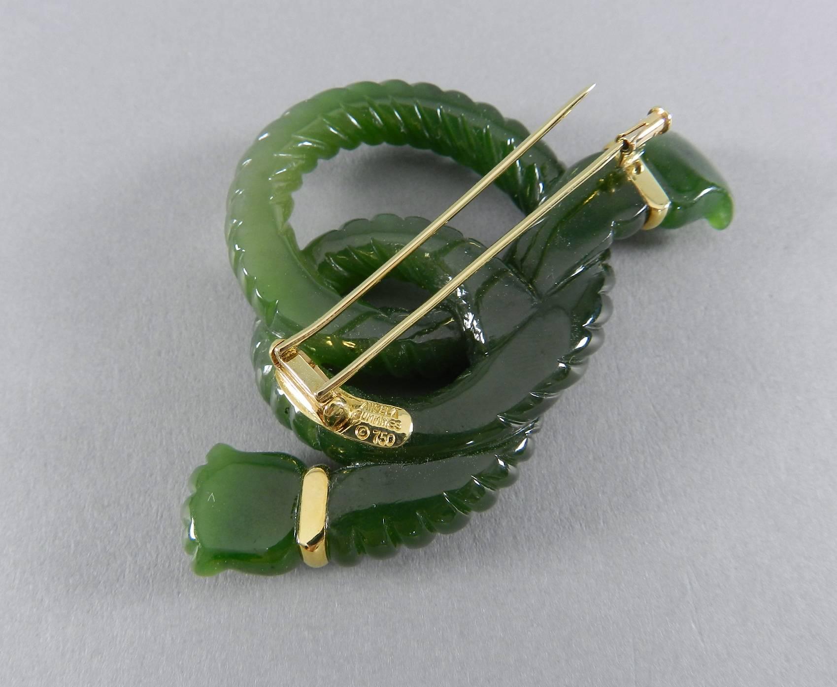 Angela Cummings green nephrite and 18k gold knot brooch.  Measures 3” x 1-7/8” .  Hallmarked “Angela Cummings © 750" on reverse and “k18” on side profile of clasp.  Double fur-clip with trombone closure. 41.2 grams.

We ship worldwide.