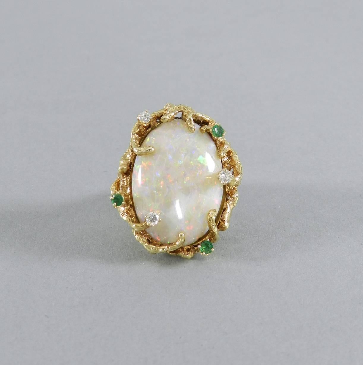 Vintage circa 1970's bold organic cocktail ring.  Large statement ring with one of a kind custom design. 14k yellow gold with opal center, diamonds, and emeralds. Ring size USA 7.  1 oval cabochon white opal - approximate total weight 21.85ct.  3