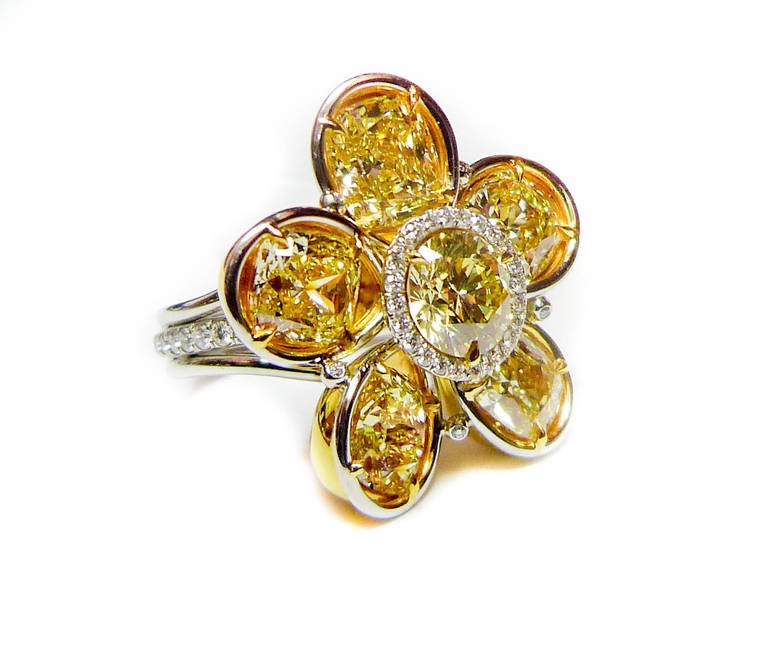 Magnificent Fancy Yellow Diamond flower Ring features 7.13 carats of diamonds totaling five GIA Certified Fancy Yellow Cushion cut Diamonds with one fancy light yellow, GIA diamond in the middle with 0.70 Carats of Micropave round diamonds around in
