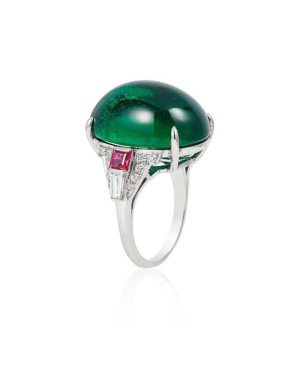 This bold ring boasts an impressive emerald cabochon weighing 25.83 carats flanked by calibré cut rubies weighing 0.63 carats and round and baguette diamonds weighing a total 0.64 carats, all mounted in platinum.