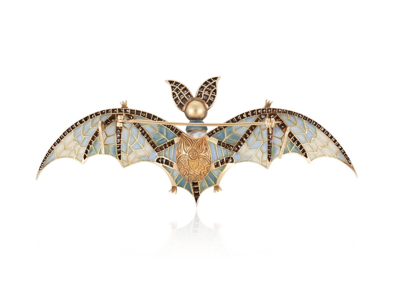 This dramatic pin depicting a bat with a very large sized natural pearl abdomen is meticulously crafted and boasts diamond trim, cabochon ruby eyes, and plique-à-jour enamel work.