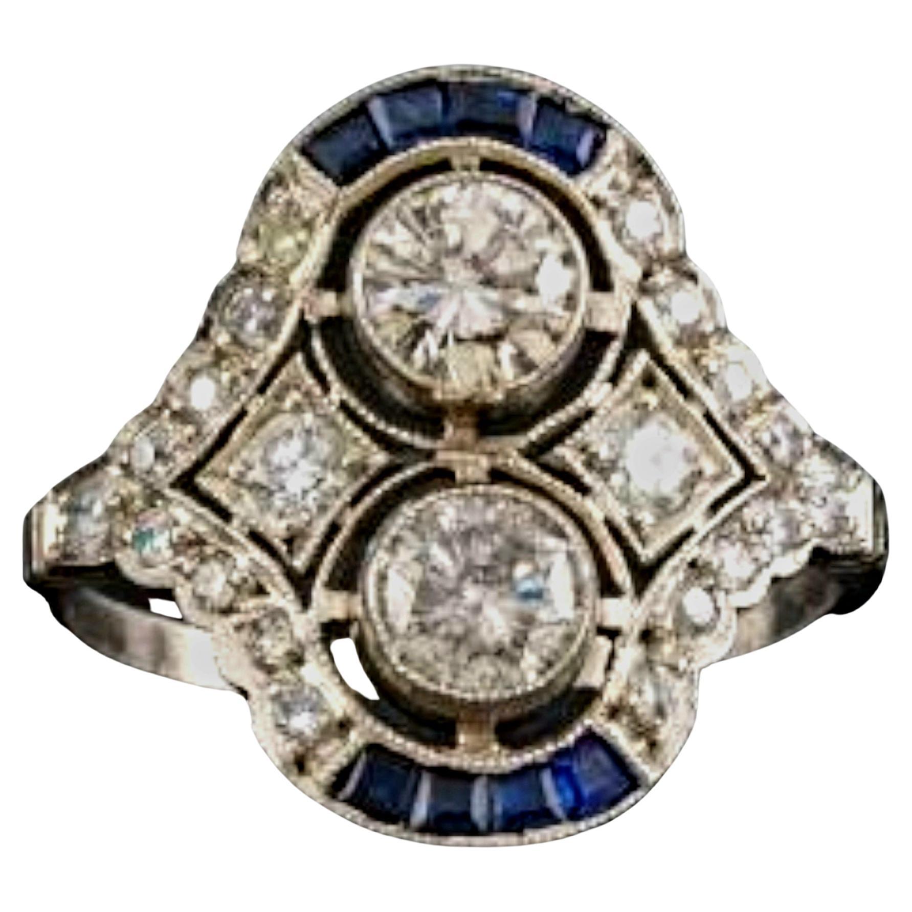 Art-Deco Style Double Diamond and Calibre Sapphire Ring.

A pair of European-cut diamonds, together weighing approx. 1 carat (approx. 0.50 carats each, color I-J, clarity SI), scintillate in tandem, cheek-to-cheek, in this dynamic Art Deco Style