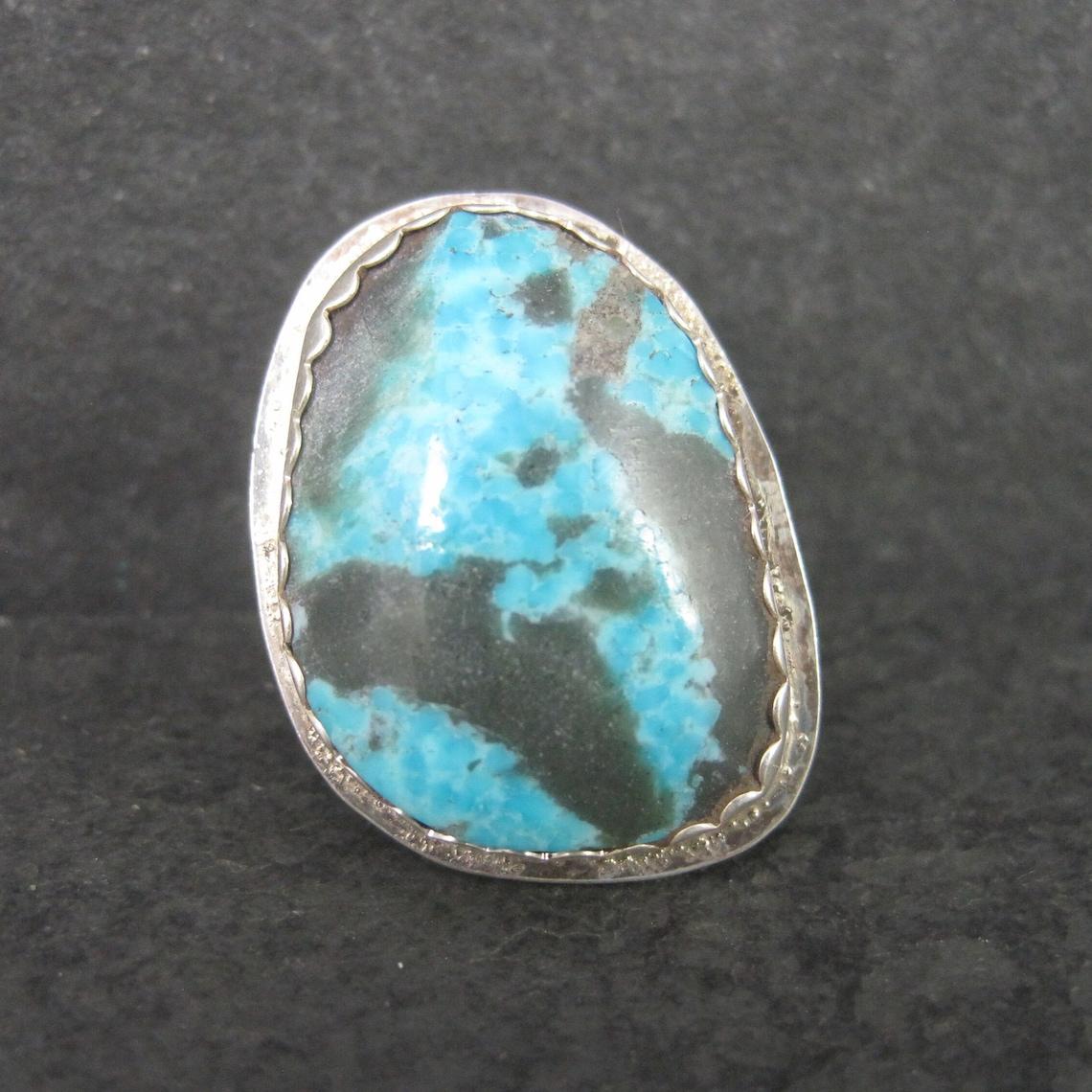 Questo bellissimo anello vintage è in argento sterling con una vera pietra turchese.
È una creazione dell'argentiere Navajo Curtis Billie.

La faccia di questo anello misura 15/16 di pollice da est a ovest e 1 3/16 di pollice da nord a