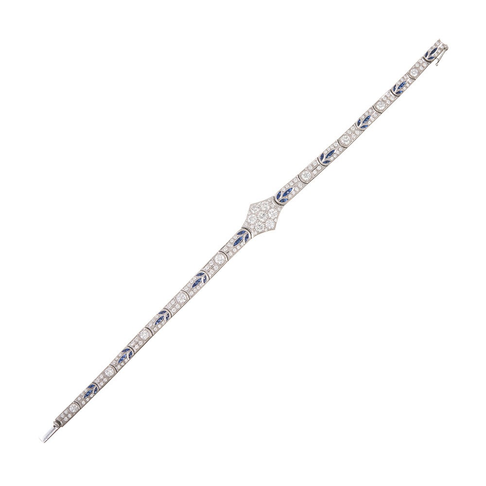 Fine original art deco bracelet made of 18k white gold. A sweet and ornately-detailed pattern of sapphire “leaves” is complimented by brilliant diamonds and finished in the center with a hexagonal diamond cluster. 130 white diamonds grade F-G color