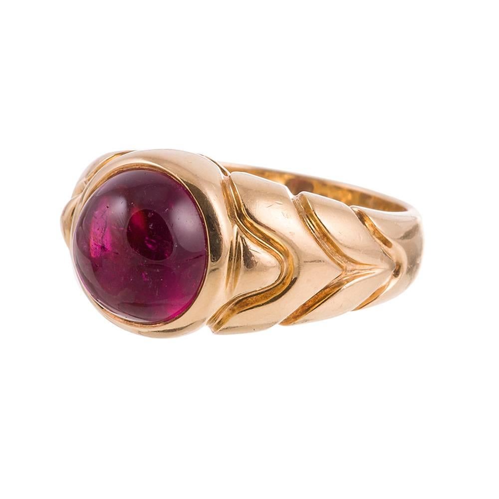 A sculpturally interesting creation to adorn your finger, compliments of style icon Bulgari. The top is set with a cabochon rubellite, bursting with a pop of color. 18k yellow gold. Size 6.75 can be resized on request. 