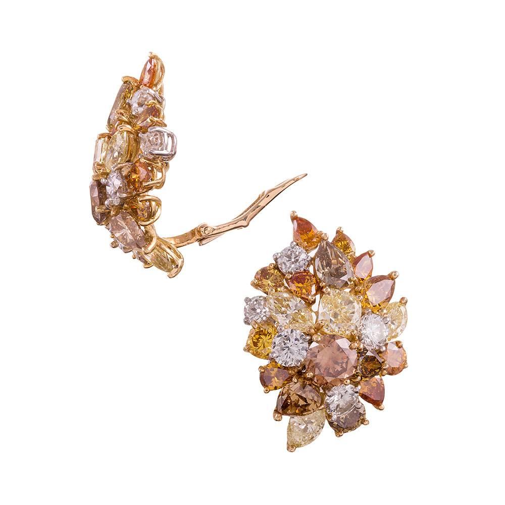 A most impressive pair of diamond ear clips, set with 12.80 carats of assorted fancy colored diamonds. The mixed shapes make this pair unusual and alluring, resembling the flames of a fire dancing on your ears, while maintaining a subtlety that is