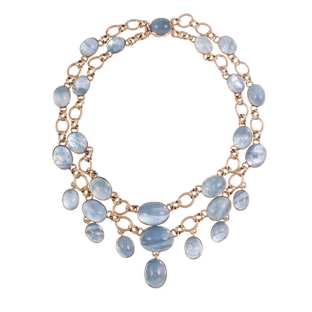 Two rows of 18 karat yellow gold bezel set cabochon aquamarines designed as a modified festoon style necklace, create an adornment that can be worn day to night. Twisted links connect high polished golden links to each gemstone-set station. The