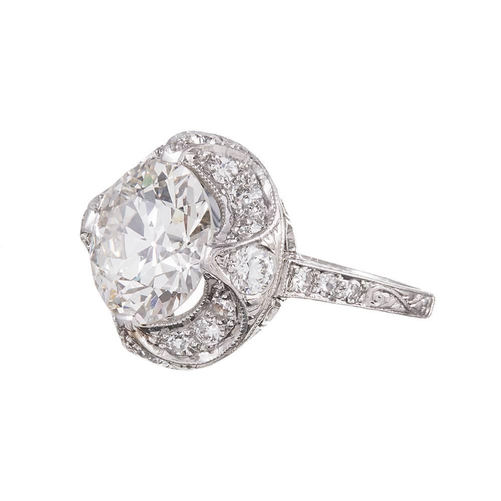 A stunning art deco design, with a 4.00 carat solitaire nested in a highly stylized four prong mounting with a scalloped border of crescent moons and a hand-pierced under gallery. Diamonds have been incorporated into every crevice, to ensure the