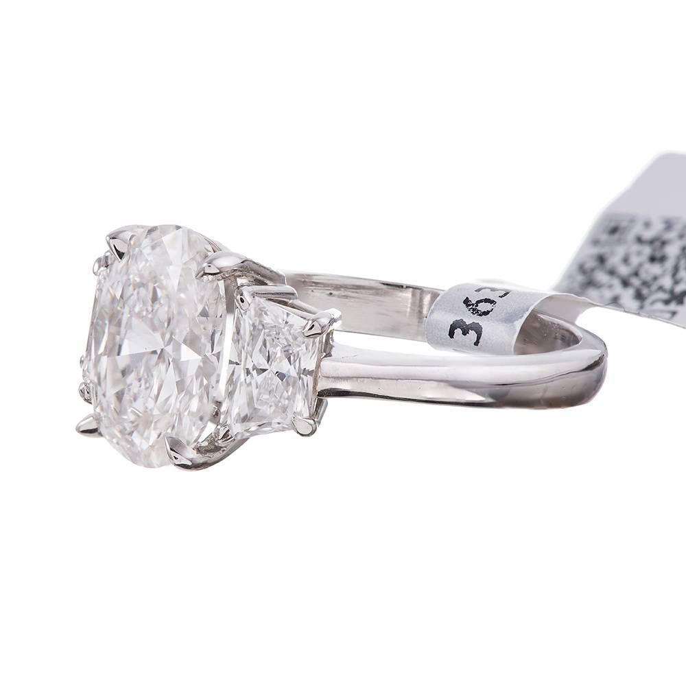 A classic creation in platinum with a pleasant collection of diamonds housing a 2.05 carat oval brilliant cut center diamond and flanked by a pair of trapezoid cut diamonds that weigh .80 carats combined.  Accompanied by an IGI appraisal report