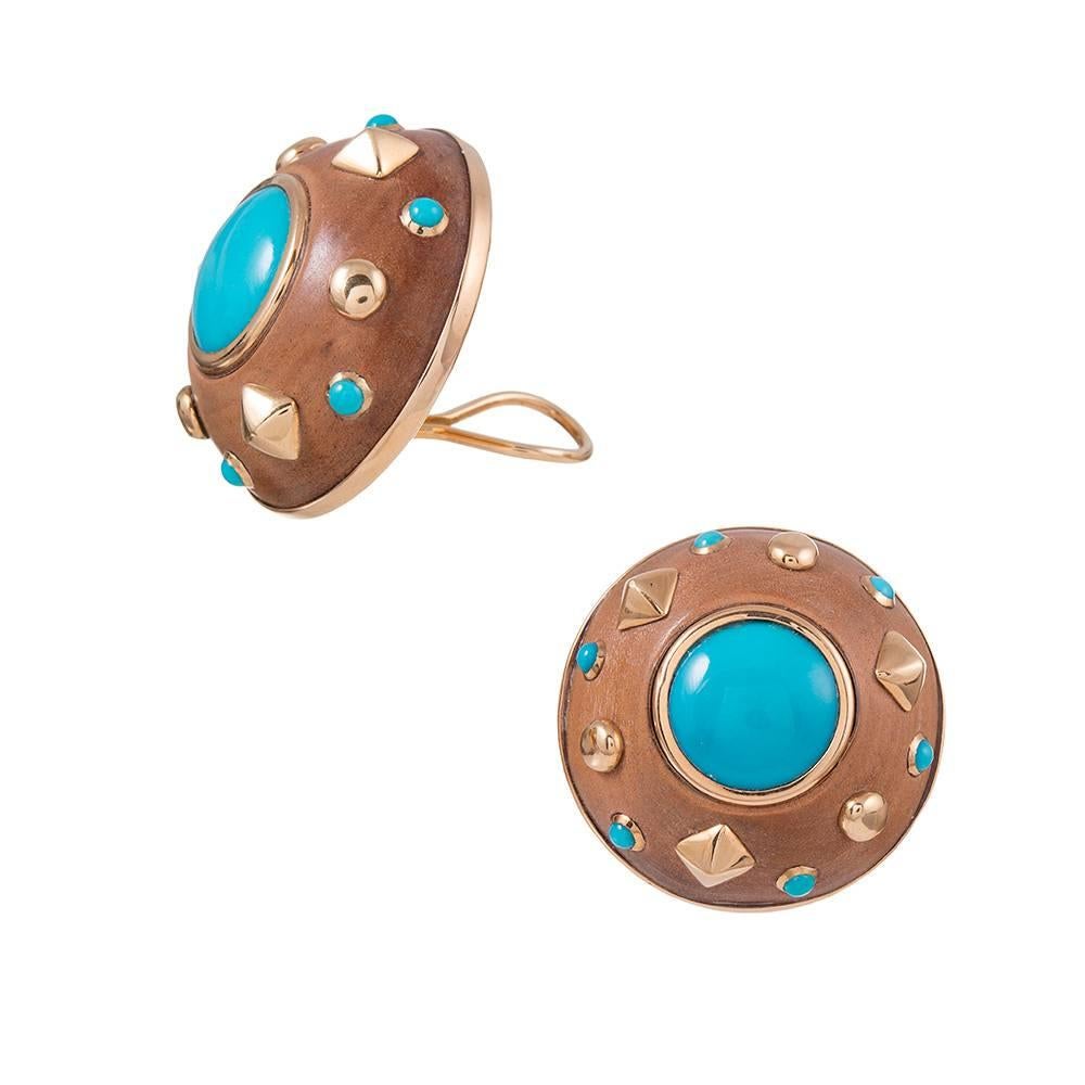 A pleasant pair of earringss, compliments of the esteemed house of Trianon, a division of famed American jeweler Seaman Schepps. These 18k yellow gold mountings contain a smooth sandalwood disc decorated with turquoise cabochons and golden studs.