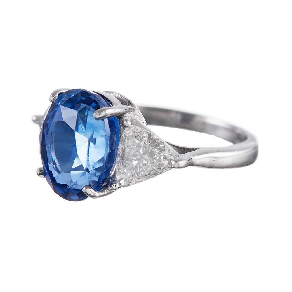 A classic creation set in the center with a 7.02 carat oval brilliant sapphire an flanked by a pair of trillion diamonds. The diamonds weigh 1.00 carat combined and are the ideal accent for the major stone, tapering down the sides and allowing the