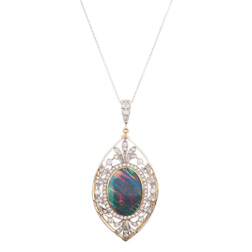 A platinum and 18 karat yellow gold filigree frame surrounds an oval opal in classic Edwardian splendor. Approximately 2.00 carats of diamonds create the floral-themed border, with each edge finished with millgrain. The opal is of extremely high