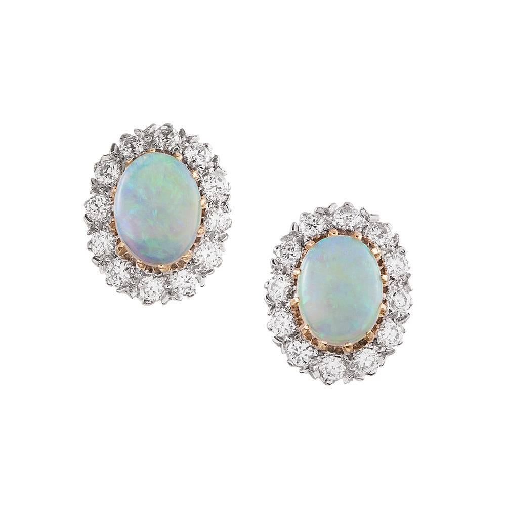 A modern rendering of a classic style, with cabochon oval opals framed in brilliant round white diamonds. The opals weigh 1.49 carats in total, while complimented by .56 carats of diamonds. Made of 18 karat white and yellow gold, these are of new