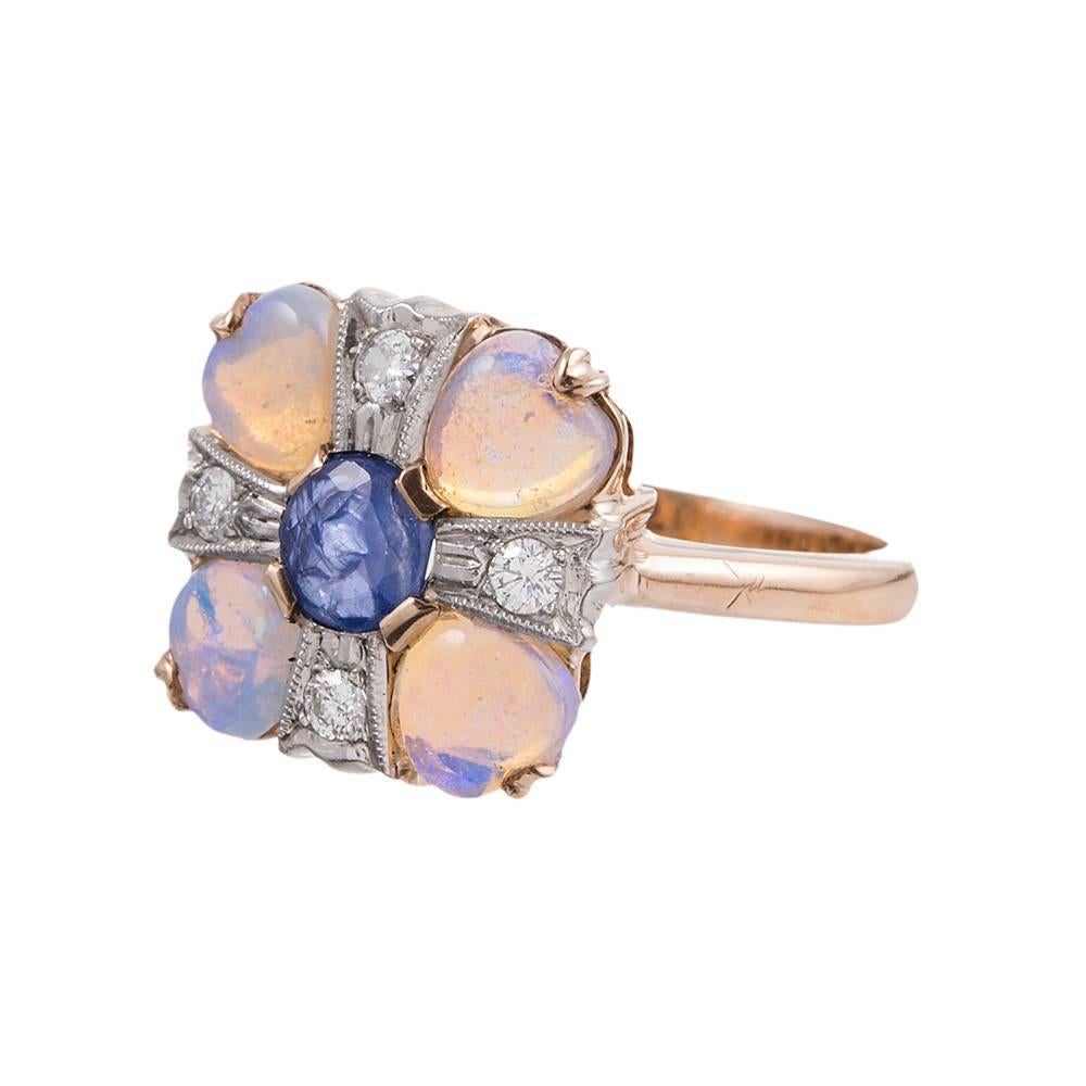 A 10k yellow gold ring decorated with a cushion-shaped cluster of opal, sapphire and diamonds. A lovely vintage treasure with a comfortable low profile. The sapphires measure 4.7 x 1.7mm, 1/3 of a carat. The opals are 5.7 x 5 x 1.9, 1/4 of a carat