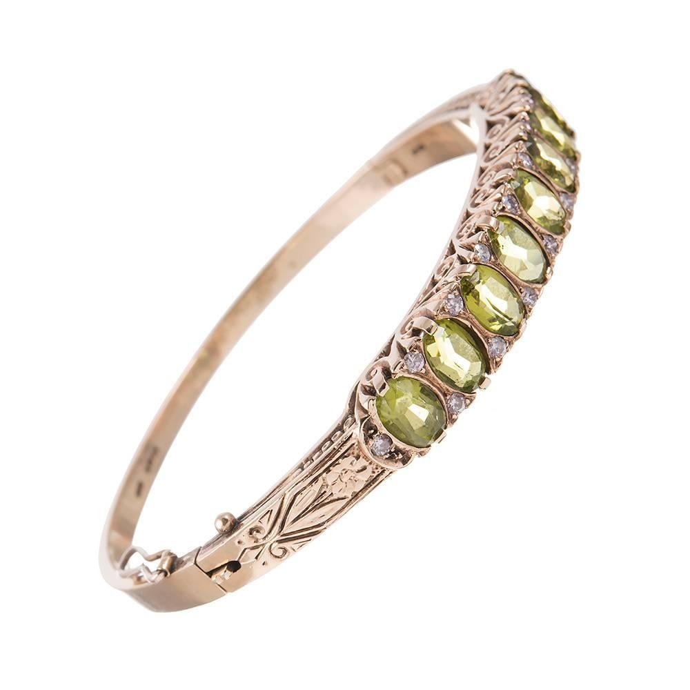 An ever-popular style with antique jewelry enthusiasts, this English carved bangle bracelet is rendered in  9 carat gold and decorated with peridot and diamonds. Note the extensive scrolling design on this piece. The style lends itself to daily rare